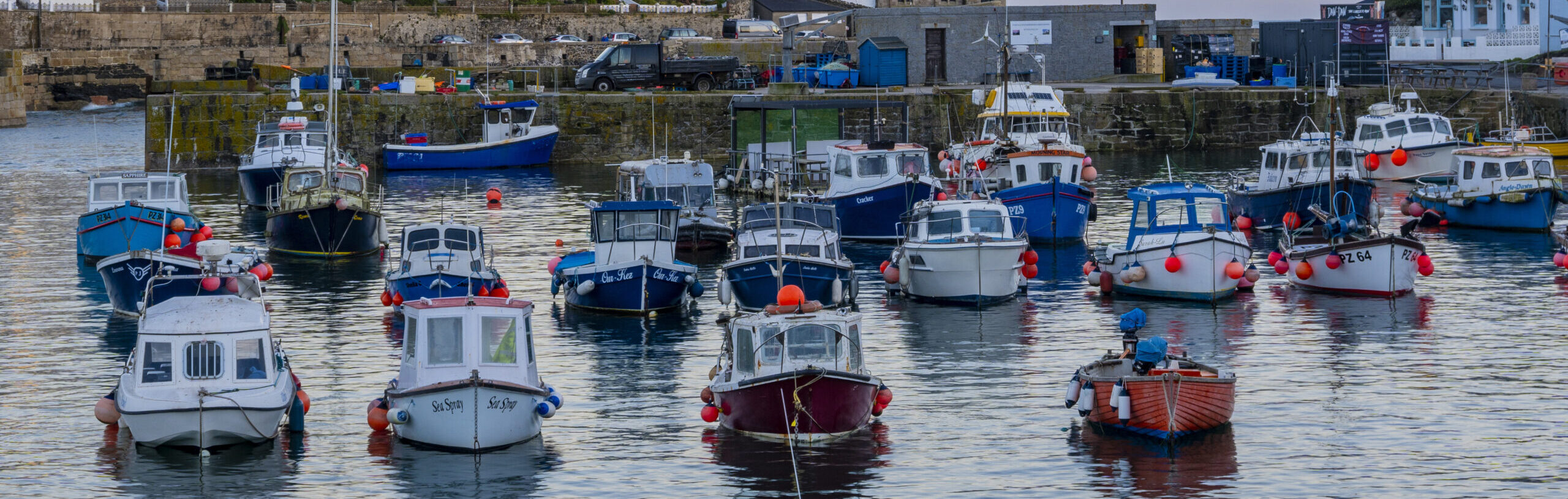 Many small fishing boats in a harbour at dawn.